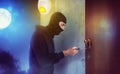 Thief with balaclava tries to open the door of apartment with a key Royalty Free Stock Photo