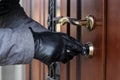 A thief in gloves opens the door lock of a private house and penetrates inside Royalty Free Stock Photo