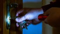 A thief opens the door at night with a flashlight. Burglary of the apartment, illegal penetration into the dwelling_