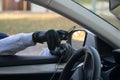 The thief`s hand in a black glove, takes the smartphone from the front of the car, through the open glass, breaking the wire Royalty Free Stock Photo