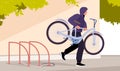 Thief stealing bicycle from rack in public city area, bike theft on street by man Royalty Free Stock Photo