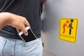 Thief stealing mobile phone from back pocket of a woman with beware pickpockets sign symbol background. Royalty Free Stock Photo