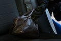Thief steals a womanÃ¢â¬â¢s brown bag from the rear of a car Royalty Free Stock Photo