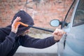 Thief trying to pick the lock of parked car Royalty Free Stock Photo