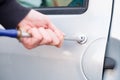 Thief trying to pick the lock of parked car Royalty Free Stock Photo