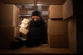Thief wears gloves steal boxes of goods in a warehouse in the dark. Concept of problems with theft of postal parcels