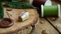 Thimble on a Wooden Plaque with Spools of Thread, Sewing Needles and Buttons