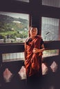 Thimphu, Bhutan - September 10, 2016: Young novice Buddhist monk in reddish orange robes standing in front of a window. Royalty Free Stock Photo