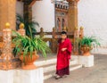 Thimphu, Bhutan - September 10, 2016: Young novice Buddhist monk wearing traditional clothing standing near the temple entrance. Royalty Free Stock Photo