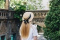 A thin blonde girl with long hair in a white dress stands with her back to the camera and looks into the distance in a wide- Royalty Free Stock Photo