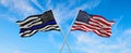 Thin Blue Line. Black Flag of USA with Police Blue Line waving in the wind on flagpole against the sky with clouds on sunny day. Royalty Free Stock Photo