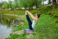 Thin brunette girl sitting in Both big toe exercise, Paripurna Navasana pose  in a summer park. Green forest on the background. Royalty Free Stock Photo