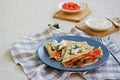 Thin crepe pancakes with salted salmon and cream cheese on a gray plate on a light concrete background