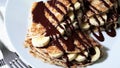 Thin crepes with banana and chocolate on white plate.