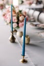 A thin elegant blue candle in a stylish metal candlestick in wedding decor Royalty Free Stock Photo