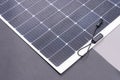 Thin flexible mobile solar panel with cable for connection. Royalty Free Stock Photo