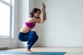 Thin girl in activewear doing yoga exercise Garudasana or Eagle pose with bare feet on mat in sports club Royalty Free Stock Photo
