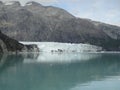 Thin Glacier between two mountains slowly gliding into the pacific ocean with a cloudy backdrop Royalty Free Stock Photo