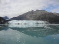 Thin Glacier between two mountains slowly gliding into the pacific ocean with a cloudy backdrop Royalty Free Stock Photo