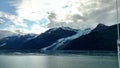 Thin Glacier between two mountains slowly gliding into the pacific ocean with a cloudy backdrop