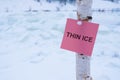 Thin ice is written on a piece of paper that is attached to a pole