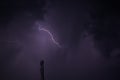 Thin lightening bolt in the sky. lightening with dark clouds in background.