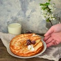 Thin pancakes with cherries. Pancakes in a white plate. Wood background. Plate with food in the hands