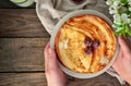 Thin pancakes with cherries. Pancakes in a white plate. Wood background. Plate with food in the hands