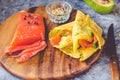 Thin pancakes with red fish on plate, top view.Crepes with filet salmon and cheese, red fish and green avocado on white plate over