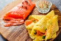 Thin pancakes with red fish on plate, top view.Crepes with filet salmon and cheese, red fish and green avocado on white plate over