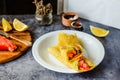 Thin pancakes with red fish on plate, top view.Crepes with filet salmon and cheese, red fish and green avocado on white plate over