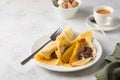 Thin pancakes stuffed with caramelized bananas and chocolate spread on a white plate against a light concrete background. Royalty Free Stock Photo