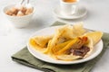 Thin pancakes stuffed with caramelized bananas and chocolate spread on a white plate against a light concrete background. Royalty Free Stock Photo