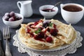 Thin pancakes with wheat flour, eggs and kefir, served with berries, jam and cup of cofee on gray table. Closeup Royalty Free Stock Photo