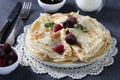 Thin pancakes with wheat flour, eggs and kefir, served with berries, jam and a glass of milk on gray table Royalty Free Stock Photo