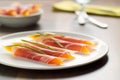 thin prosciutto slices draped over fresh cantaloupe wedges on white plate