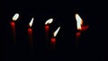 Thin red candles on a black background, panoranic