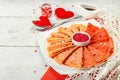 Thin red crepes or pancakes with raspberry sugar and sweet hearts pastry topping