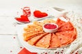 Thin red crepes or pancakes with raspberry sugar and sweet hearts pastry topping