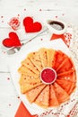 Thin red crepes or pancakes with raspberry sugar and sweet hearts pastry topping