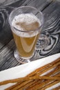 Thin sausages for beer. On a rectangular plate. Next to it is a glass of wheat beer. Background from pine boards. Close-up Royalty Free Stock Photo
