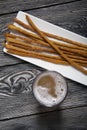 Thin sausages for beer. On a rectangular plate. Next to it is a glass of wheat beer. Background from pine boards. Close-up Royalty Free Stock Photo