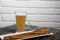Thin sausages for beer. On a rectangular plate. Next to it is a glass of wheat beer. Background from pine boards. Close-up Royalty Free Stock Photo