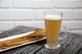 Thin sausages for beer. On a rectangular plate. Next to it is a glass of wheat beer. Background from pine boards. Close-up Royalty Free Stock Photo