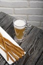 Thin sausages for beer. On a rectangular plate. Next to it is a glass of wheat beer. Background from pine boards. Close-up Royalty Free Stock Photo