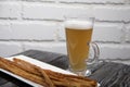 Thin sausages for beer. On a rectangular plate. Next to it is a glass of wheat beer. Background from pine boards. Close-up Royalty Free Stock Photo