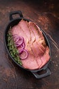 Thin sliced pastrami served in a cast iron pan with red onion rings and fresh thyme on a rustic dark textured background Royalty Free Stock Photo