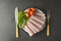 Thin slices of ham rolled on plate with fresh vegetables, dark background. Breakfast food, ingredient for sandwich. Flat lay food Royalty Free Stock Photo