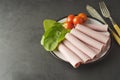 Thin slices of ham rolled on plate with fresh vegetables, dark background. Breakfast food, ingredient for sandwich. Flat lay food Royalty Free Stock Photo