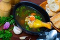 Thin soup with chicken leg in black bowl Royalty Free Stock Photo